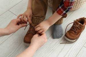 Mother helping son to tie shoe laces.